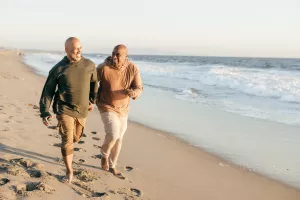 LGBTQ couple running and laughing on the beach.